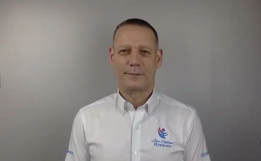 Mental Welfare Coach John Clelland wearing white shirt with a grey background